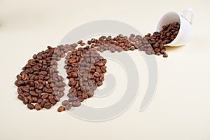 Coffee beans falling out of white cup.