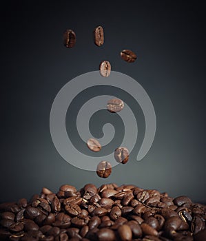 Coffee beans falling into a pile of coffee on the table