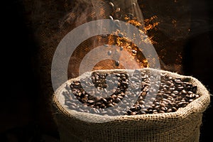 Coffee beans falling to the sack full of smoky coffee beans.