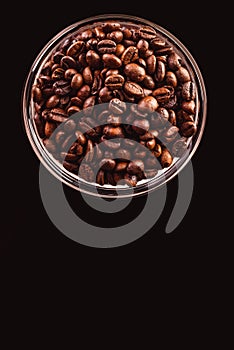 Coffee beans in glass jar standing on black background