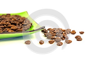 Coffee beans on a green square saucer, white background