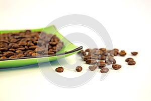 Coffee beans on a green square saucer, white background