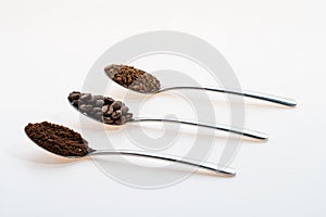 coffee beans ground instant each in its own teaspoon on a white background