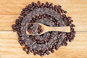 Coffee beans and ground coffee in spoon on textured wood, top-view