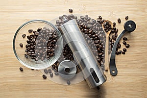 Coffee beans with hand coffee grinders bowl and wooden kitchen spoon on table background