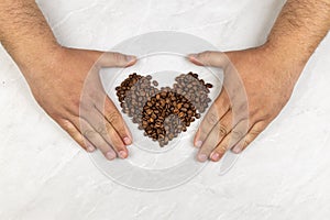 Coffee beans in heart shape on the grey marble table with copy space