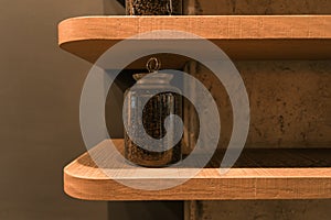 Coffee beans in jar standing on wooden shelf on wall.