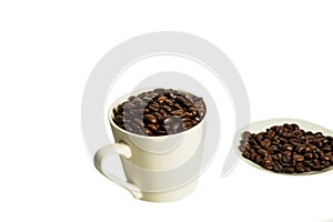 Coffee beans lie in a white mug and saucer on a white background. Isolate.