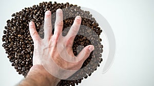Coffee beans,man`s hand touches the beans,close-up.On a white background.