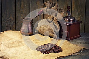 Coffee beans, manual coffee grinder and coffee maker on sacking