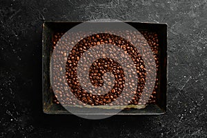 Coffee beans in a metal tray on a black stone background. Traditional drinks.