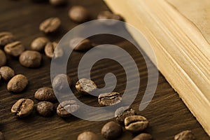 Coffee beans on old vintage open book. Menu, recipe, mock up. Wooden background.