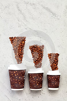 Coffee beans opposite three paper cups of different coffee capacities, vertical image photo