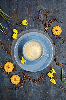 Coffee beans pattern. Blue cup of coffee, cookies and yellow tulips on a dark background. View from above