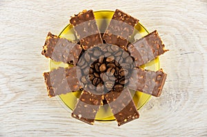 Coffee beans, pieces of chocolate in saucer on table. Top view