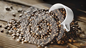 Coffee beans are poured from a Cup on a wooden background.