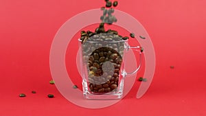 Coffee beans quickly pour, glass mug, red background. Lack of strength concept