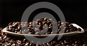 Coffee beans in a saucer on a black background