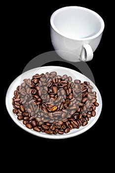 Coffee beans in a saucer with a cup.
