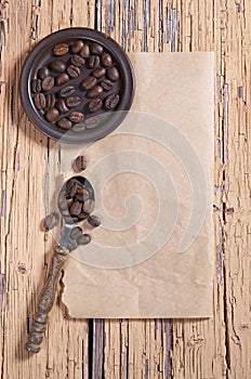 Coffee beans in saucer and spoon on a old wood