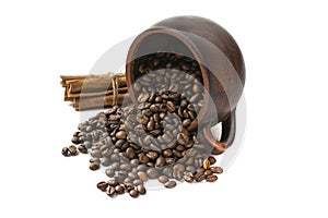 Coffee beans scattered from an inverted earthenware mug and a cinnamon stick on a white isolated background