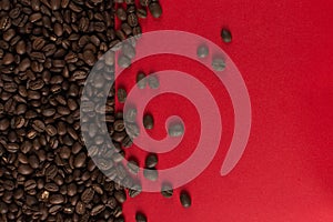 Coffee beans are scattered on a red paper background close-up, commercial copy space