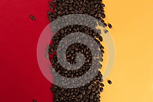 Coffee beans are scattered on a red and yellow paper background close-up, concept, commercial copy space