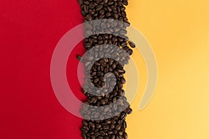 Coffee beans are scattered on a red and yellow paper background close-up, concept, commercial copy space