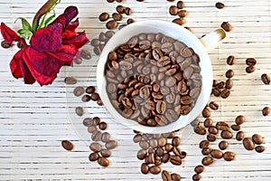 Coffee beans are scattered on the table. Dried rose on the table.