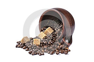 Coffee beans are scattered from an upturned earthenware mug and sugar cubes on a white isolated background