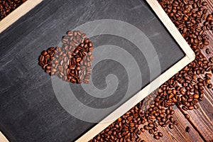 Coffee beans in the shape of heart on a black chalkboard, a lovers flower lovers for Valentine's Day