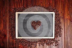 Coffee beans in the shape of heart on a black chalkboard, a lovers flower lovers for Valentine's Day