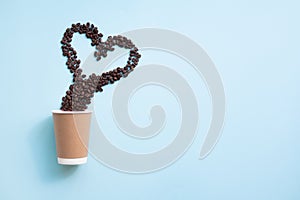 Coffee beans shaped heart symbol above paper cup.  Copy space.