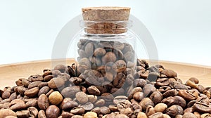 Coffee beans in a small glass jar with a cork lid on the table. Coffee beans packed in a transparent, airtight storage
