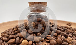 Coffee beans in a small glass jar with a cork lid on the table. Coffee beans packed in a transparent, airtight storage