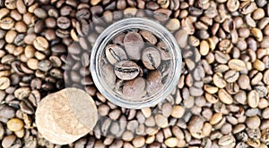 Coffee beans in a small glass jar with a cork lid on the table. Coffee beans packed in a transparent, airtight storage