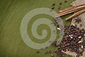 Coffee beans and some spices on green background