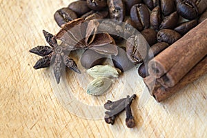 Coffee beans with spices on wooden surface