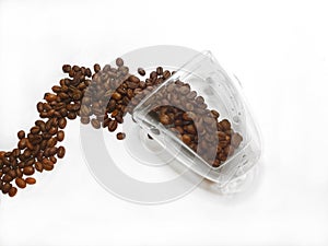 coffee beans spilled from glass cup on white background