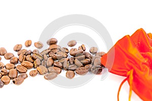 Coffee beans spilled from a red silk bag close-up with white background