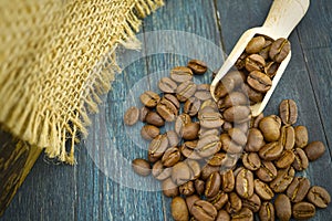 Coffee beans spilling from a wooden scoop