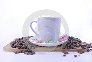 Coffee beans and sweets on the table, white cup of coffee on a saucer