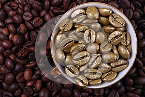 Coffee beans texture background. Golden coffee beans in a cup. Golden coffee as a symbol of quality and luxury. The concept of lux