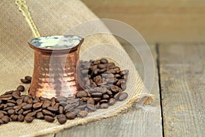 Coffee beans and traditional Turkish copper coffee pot on a burlap