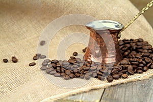 Coffee beans and traditional Turkish copper coffee pot on a burlap
