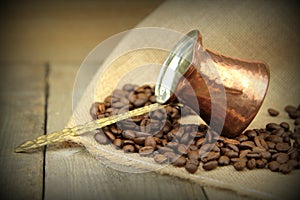 Coffee beans and traditional Turkish copper coffee pot on a burlap