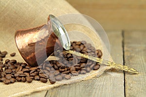 Coffee beans and traditional Turkish copper coffee pot on a burlap