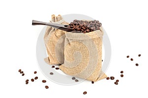 Coffee beans. Two jute burlack sacks with hard roasted coffee beans and coffee spatula,  on white background.