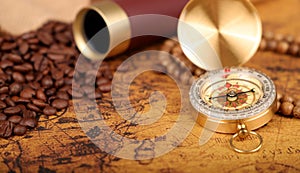 Coffee Beans and Vintage Compass with  magnifying glasson an old world map - trade and explorer concept
