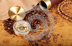 Coffee Beans and Vintage Compass with  magnifying glasson an old world map - trade and explorer concept